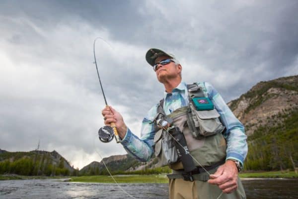 man fly fishing under cloudy skies